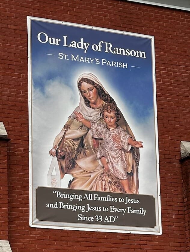 The parish's Our Lady of Ransom banner: Mary in a pale veil holding the child Jesus.
