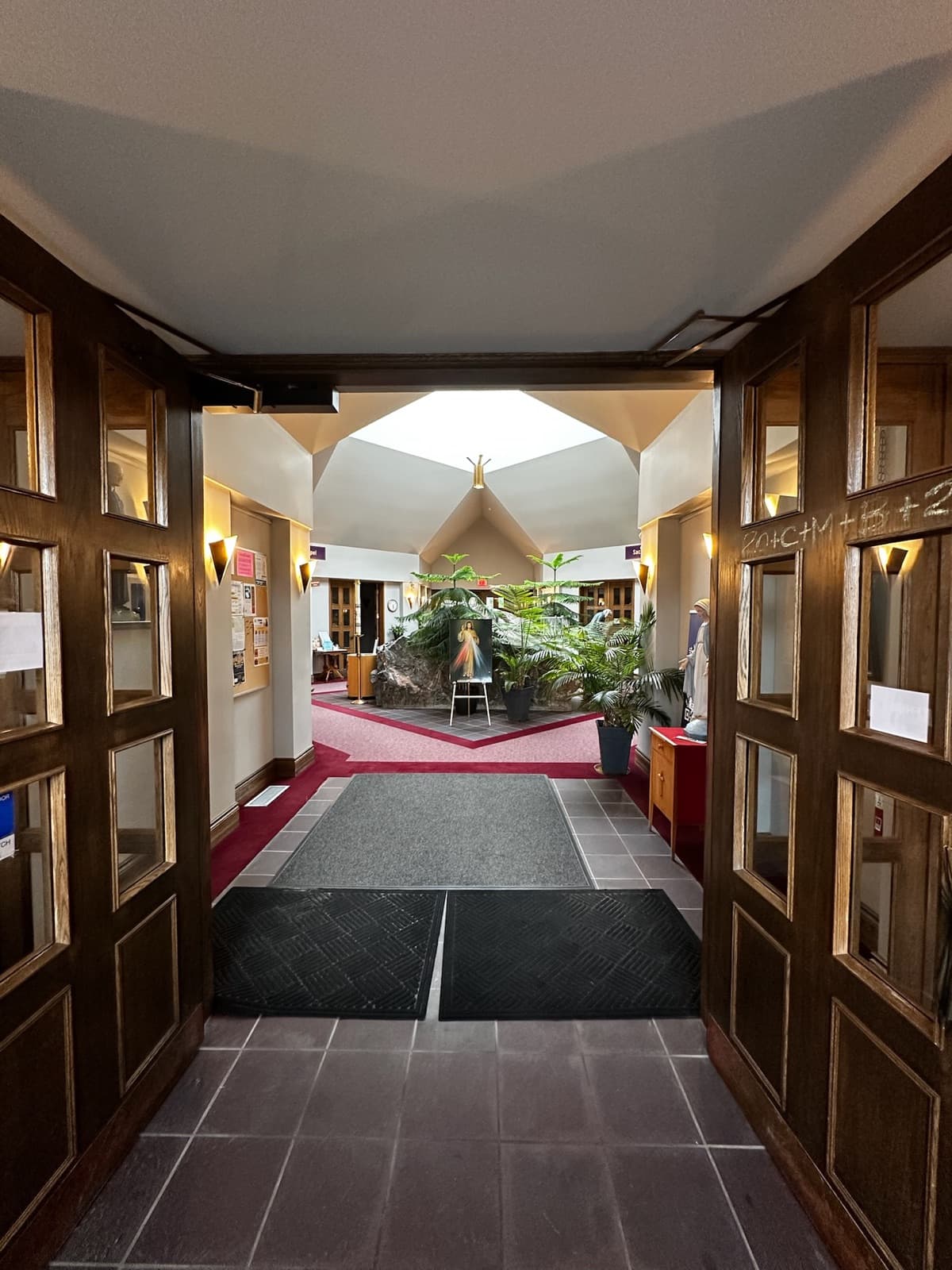Light pouring through open wooden double doors into the parish gathering area.